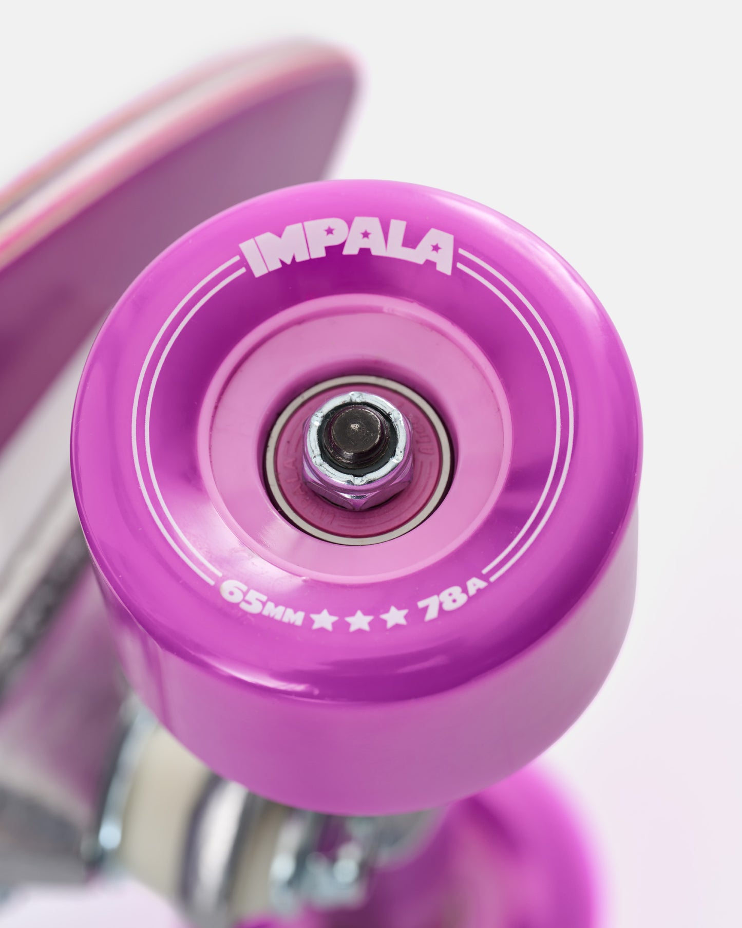 Close up of pink 65mm 78A Impala wheel showing bearing and truck on bamboo longboard