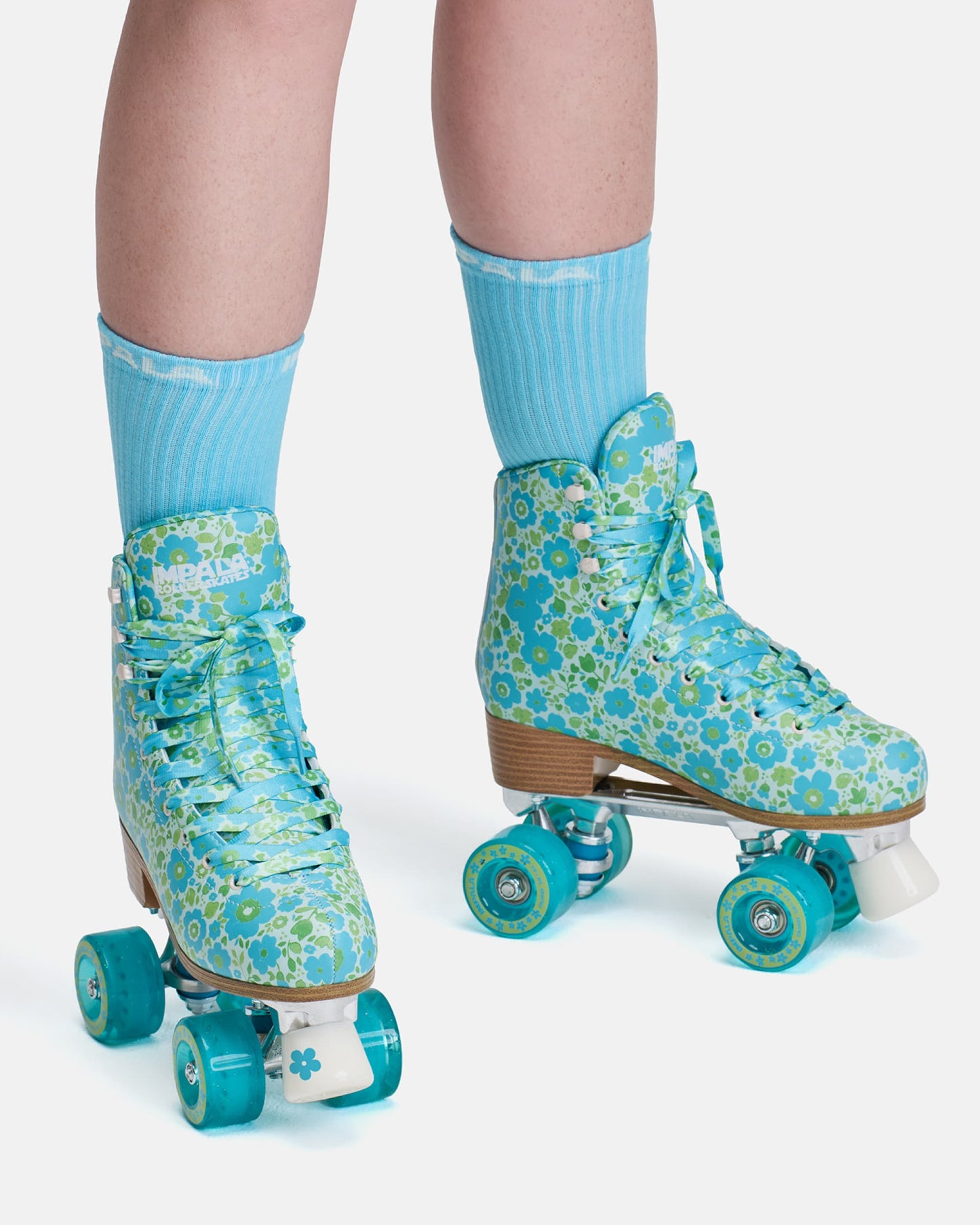 Blue floral-patterned roller skates worn with matching socks on a white background
