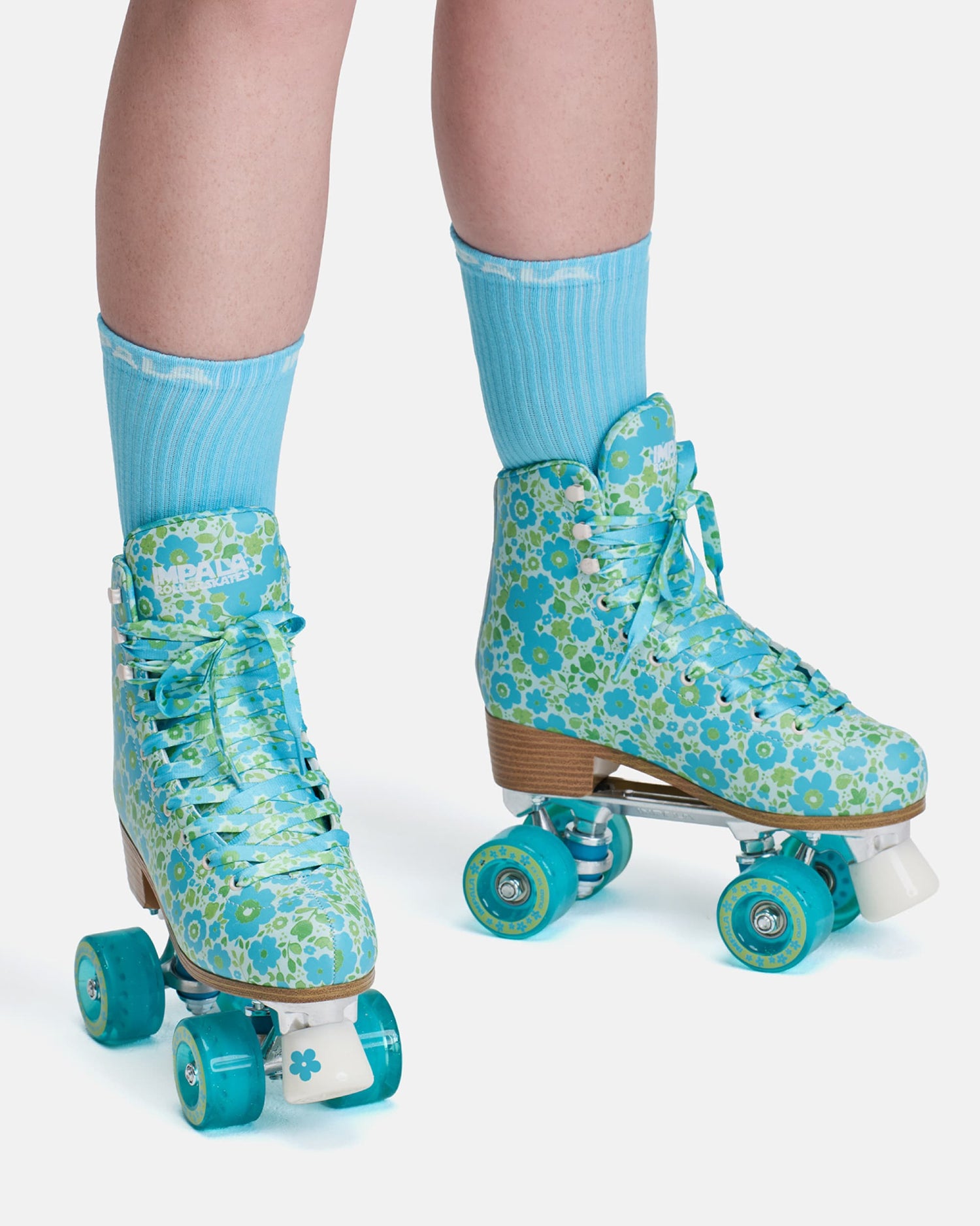 Blue floral-patterned roller skates worn with matching socks on a white background
