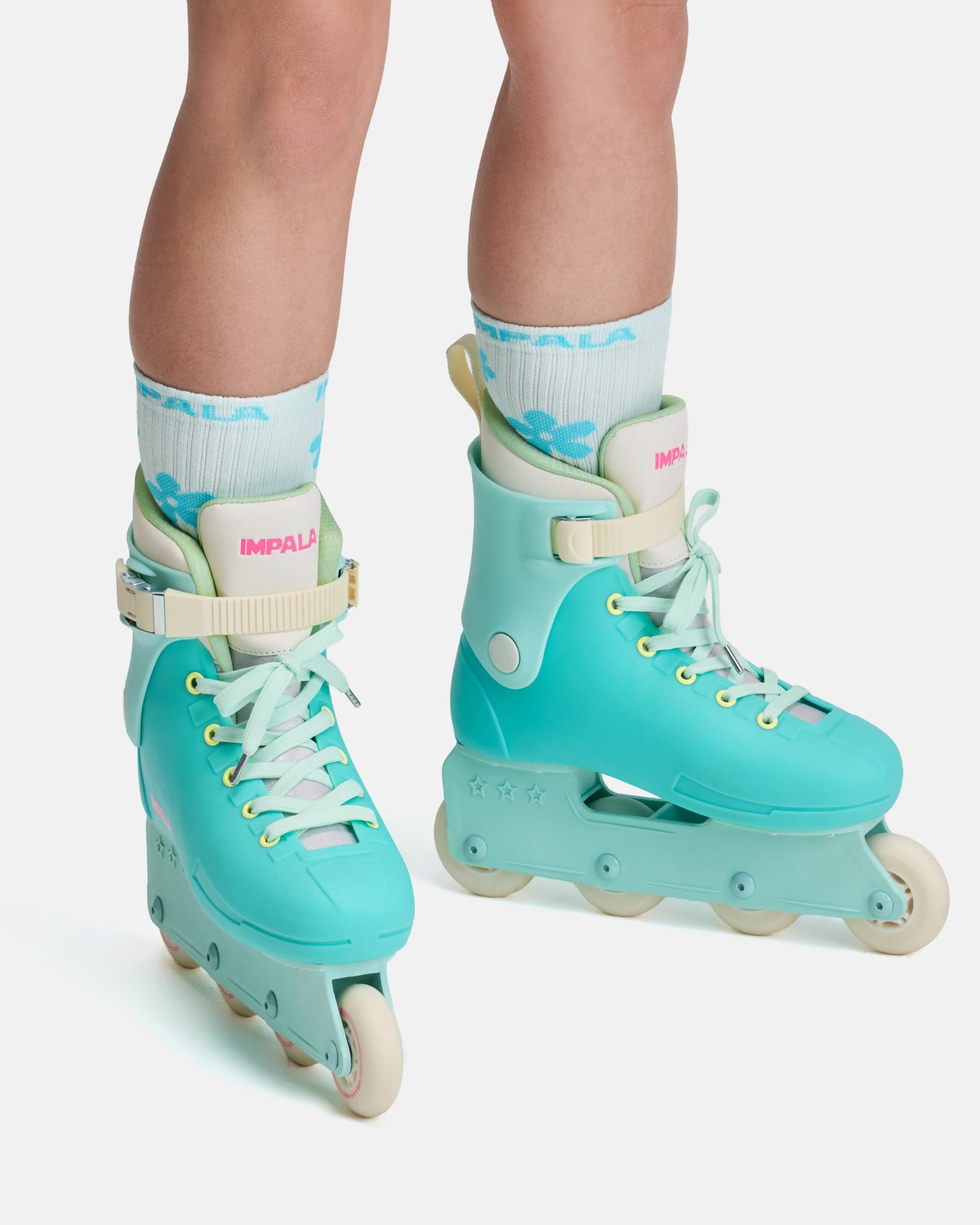 Teal inline skates with white wheels worn by a person on a light gray background