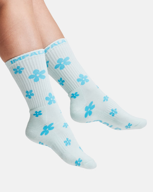 Light blue socks with blue flower patterns worn by a person on a white background